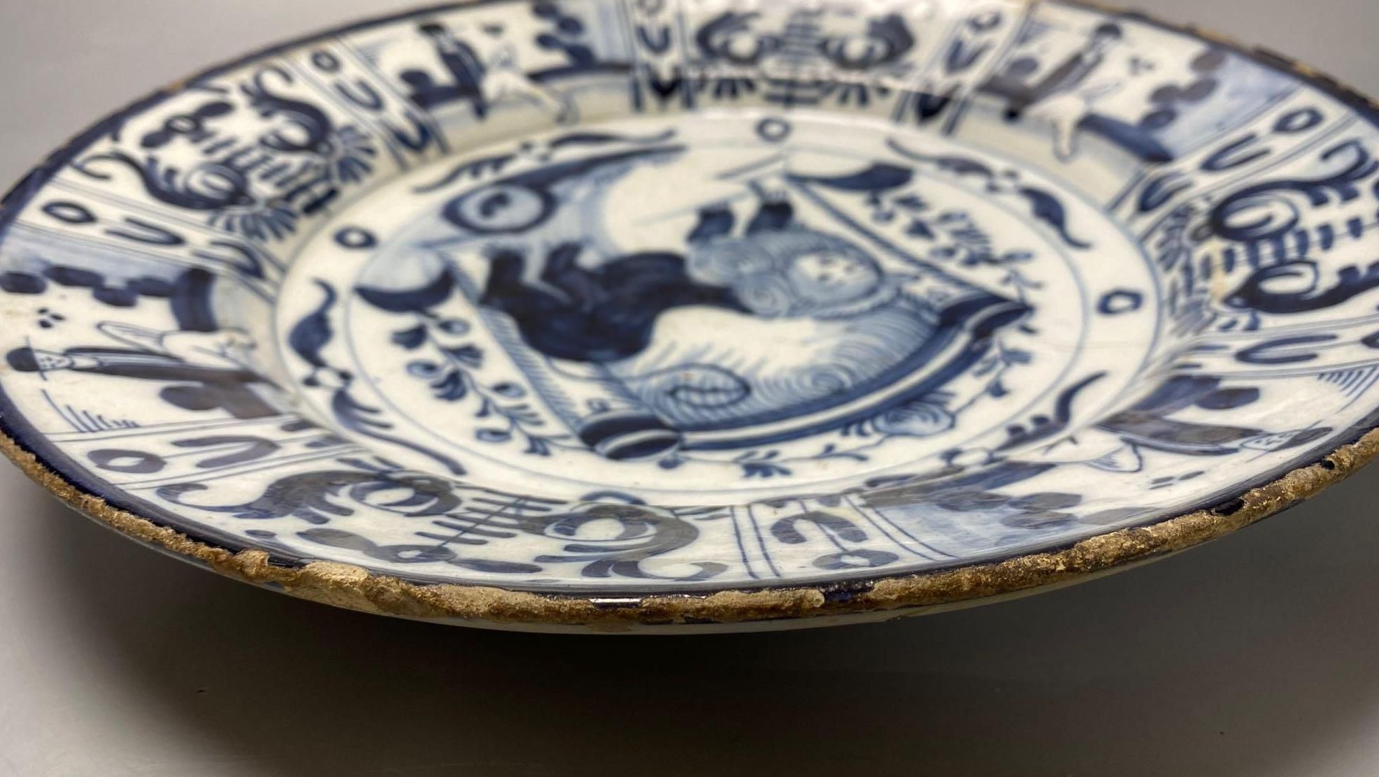 An 18th century Delft blue and white charger centred by a lion, with figural and foliate border, 32cm